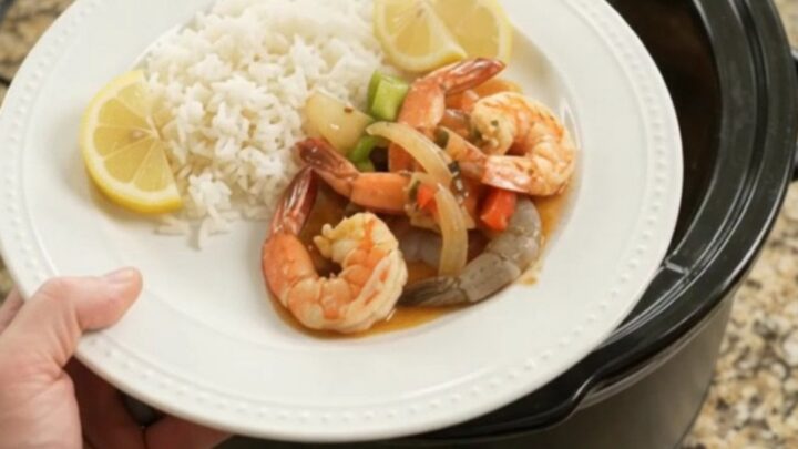 Snow crab clusters and shrimp in a slow cooker with red and green bell peppers and onions in a buttery sauce