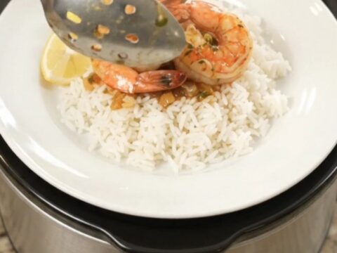 Slow cooker filled with lobster tails, shrimp, corn, and potatoes in a spicy butter sauce