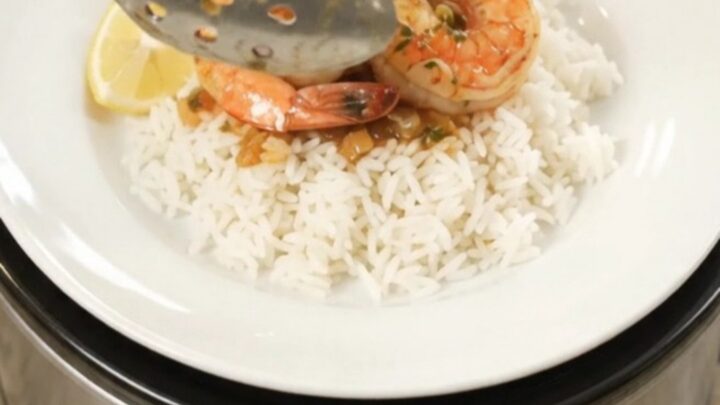Slow cooker filled with lobster tails, shrimp, corn, and potatoes in a spicy butter sauce
