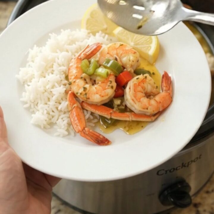 Slow cooker filled with snow crab clusters and shrimp in a garlic butter sauce with bell peppers and onions
