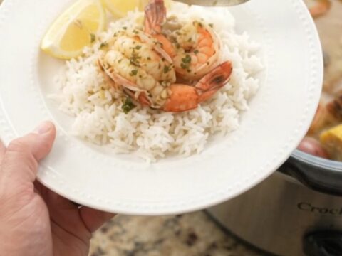 Slow-cooker seafood boil with lobster tails, shrimp, corn, and potatoes in a garlic butter sauce.