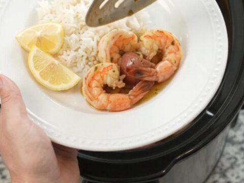 Slow cooker filled with lobster tails, shrimp, corn, and potatoes in chili-lime butter