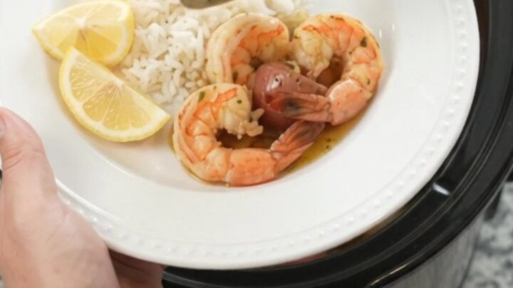 Slow cooker filled with lobster tails, shrimp, corn, and potatoes in chili-lime butter