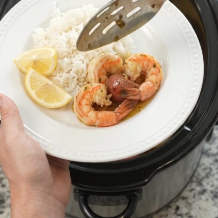 Slow cooker filled with lobster tails, shrimp, corn, and potatoes in chili-lime butter