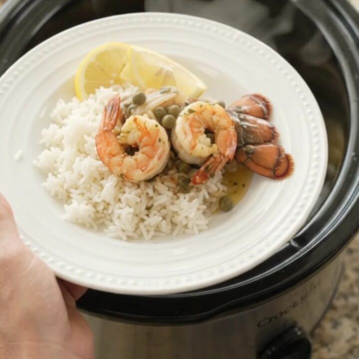 Slow cooker lobster tails and shrimp in a golden butter sauce with lemon slices and capers.