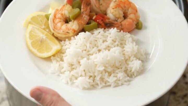 Crockpot with lobster tails and shrimp in golden butter sauce, garnished with herbs