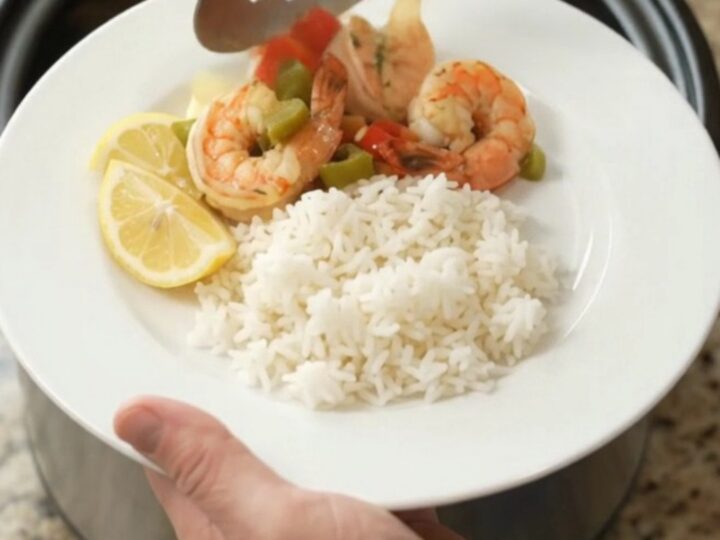 Crockpot with lobster tails and shrimp in golden butter sauce, garnished with herbs
