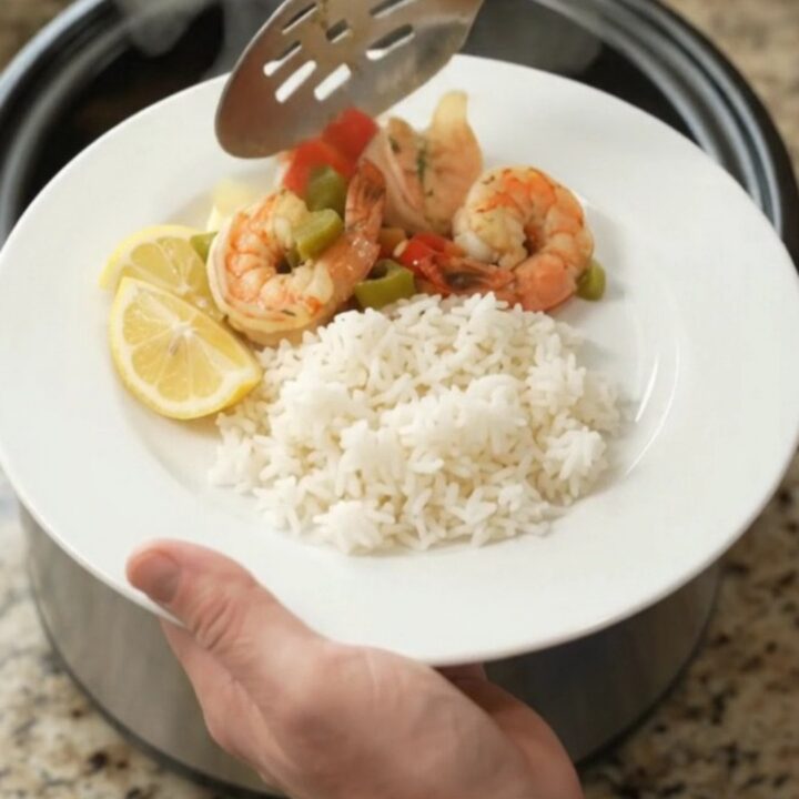 Crockpot with lobster tails and shrimp in golden butter sauce, garnished with herbs