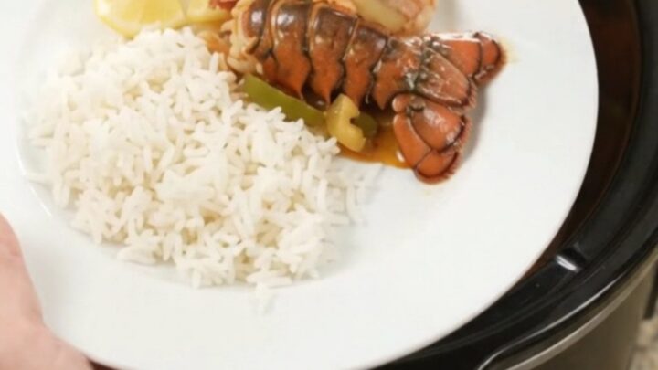 Slow-cooker lobster tails and shrimp in spicy Cajun butter sauce with bell peppers and onions, served over rice.
