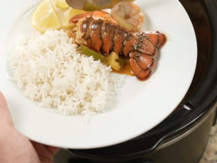 Slow-cooker lobster tails and shrimp in spicy Cajun butter sauce with bell peppers and onions, served over rice.