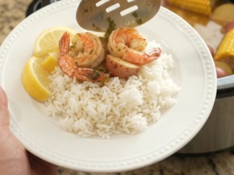 Slow cooker seafood boil with scallops, shrimp, corn, and potatoes in butter sauce