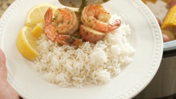 Slow cooker seafood boil with scallops, shrimp, corn, and potatoes in butter sauce