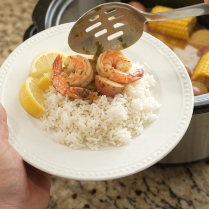Slow cooker seafood boil with scallops, shrimp, corn, and potatoes in butter sauce