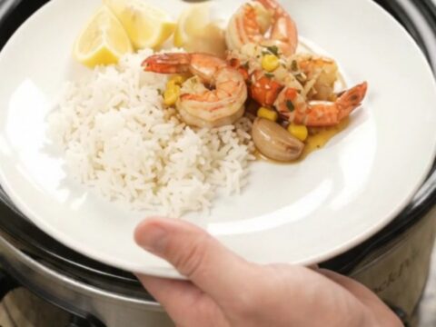 Slow cooker filled with lobster tails, shrimp, corn, and garlic in chili-lime butter