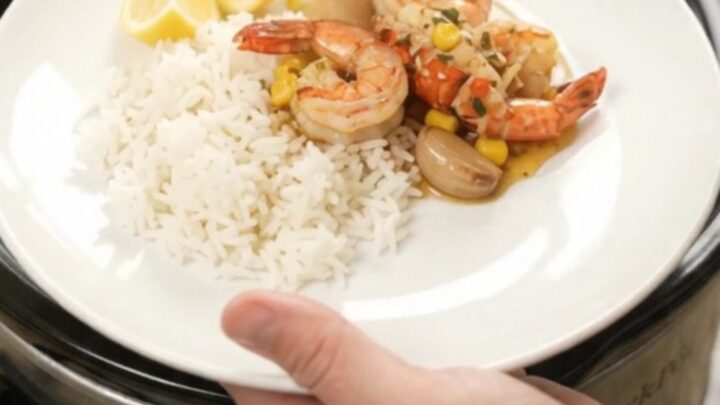 Slow cooker filled with lobster tails, shrimp, corn, and garlic in chili-lime butter