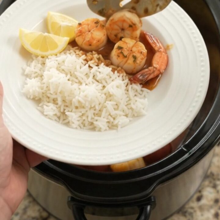 Slow cooker bayou butter Cajun boil with scallops, shrimp, corn, and potatoes in a rich red sauce.