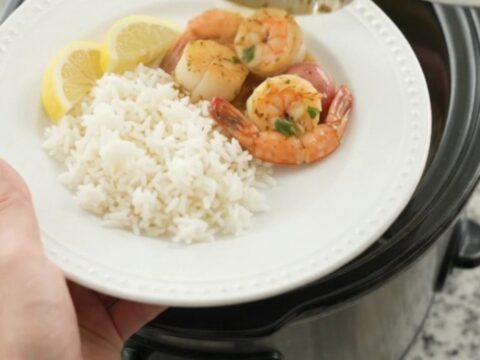 Crockpot chili lime butter seafood boil with scallops, shrimp, corn, and potatoes in a glossy sauce