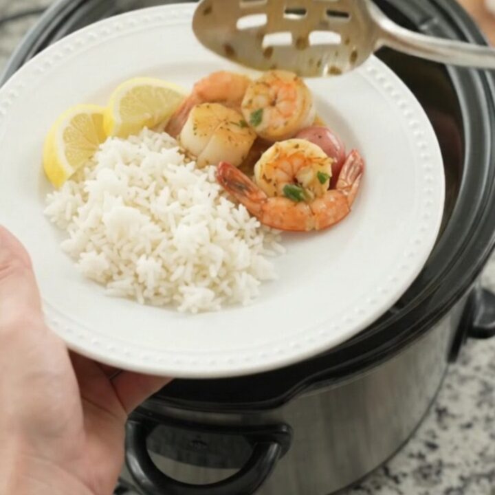 Crockpot chili lime butter seafood boil with scallops, shrimp, corn, and potatoes in a glossy sauce