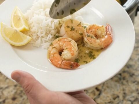Slow cooker filled with golden sea scallops, shrimp, corn, and potatoes in a buttery herb sauce