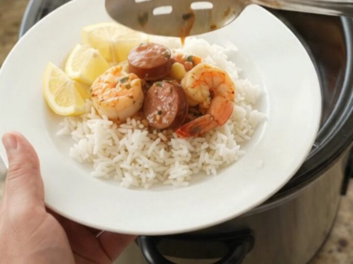Slow cooker filled with scallops, shrimp, andouille, and potatoes in a red butter sauce.