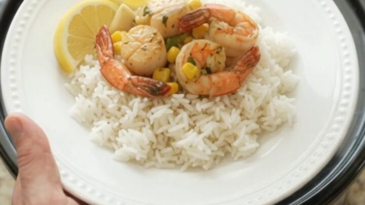 Slow cooker filled with sea scallops, shrimp, corn, and garlic in chili-lime butter sauce