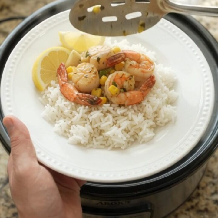 Slow cooker filled with sea scallops, shrimp, corn, and garlic in chili-lime butter sauce