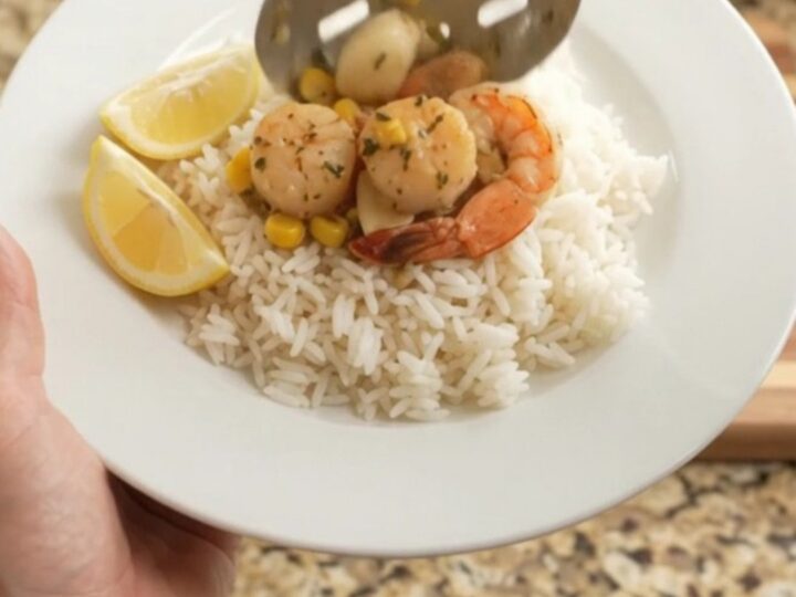 Slow cooker filled with scallops, shrimp, corn, and garlic in a golden butter sauce