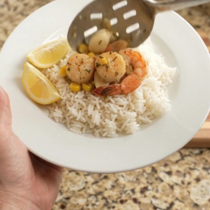 Slow cooker filled with scallops, shrimp, corn, and garlic in a golden butter sauce
