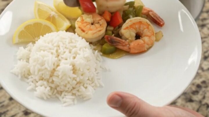 Slow cooker with golden scallops and shrimp in garlic butter sauce with bell peppers and onions.