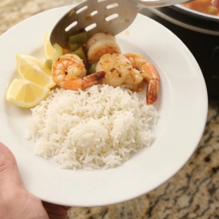 Slow cooker filled with sea scallops and shrimp in a crimson Cajun butter sauce with bell peppers and onions.