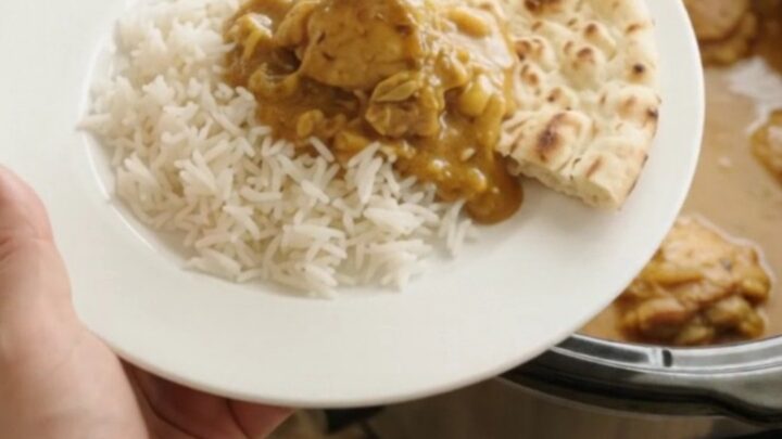 Slow cooker full of creamy golden korma chicken thighs with steam rising