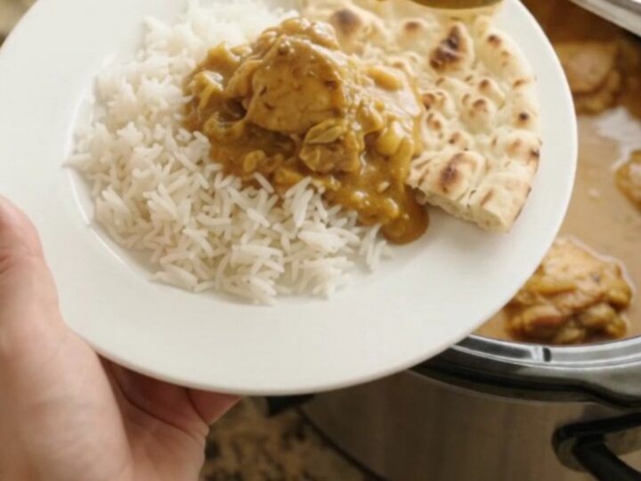 Slow cooker full of creamy golden korma chicken thighs with steam rising