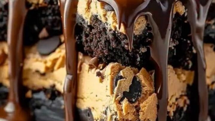 A decadent brownie cake topped with a thick layer of cookie dough and glossy chocolate ganache drips.