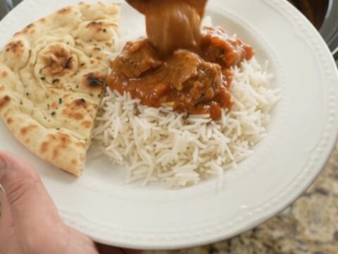 Slow cooker lamb tikka masala in a black crockpot with creamy sauce