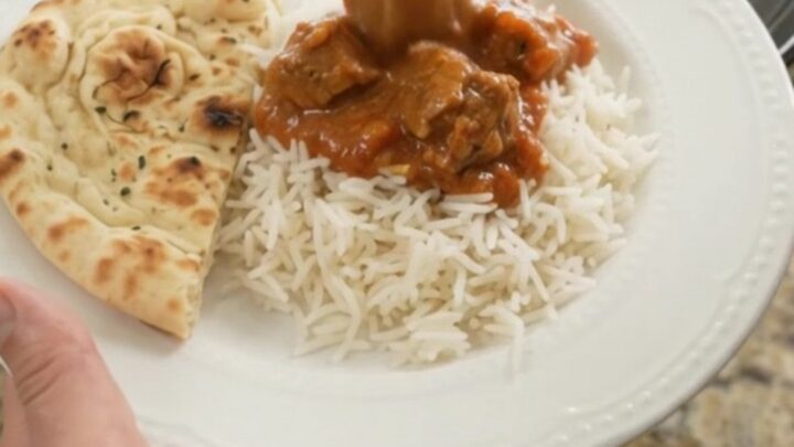 Slow cooker lamb tikka masala in a black crockpot with creamy sauce