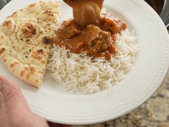 Slow cooker lamb tikka masala in a black crockpot with creamy sauce
