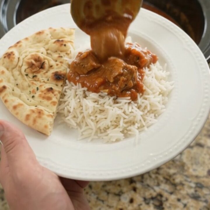 Slow cooker lamb tikka masala in a black crockpot with creamy sauce