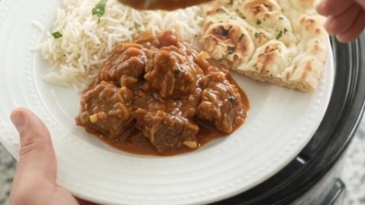 Slow cooker filled with bubbling garlic butter tikka masala lamb cubes
