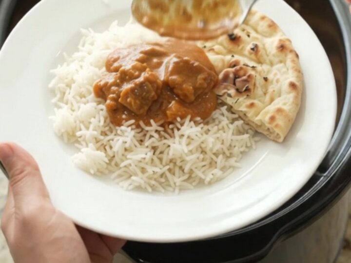 Slow-cooker makhani lamb with orange-red sauce in a black crockpot
