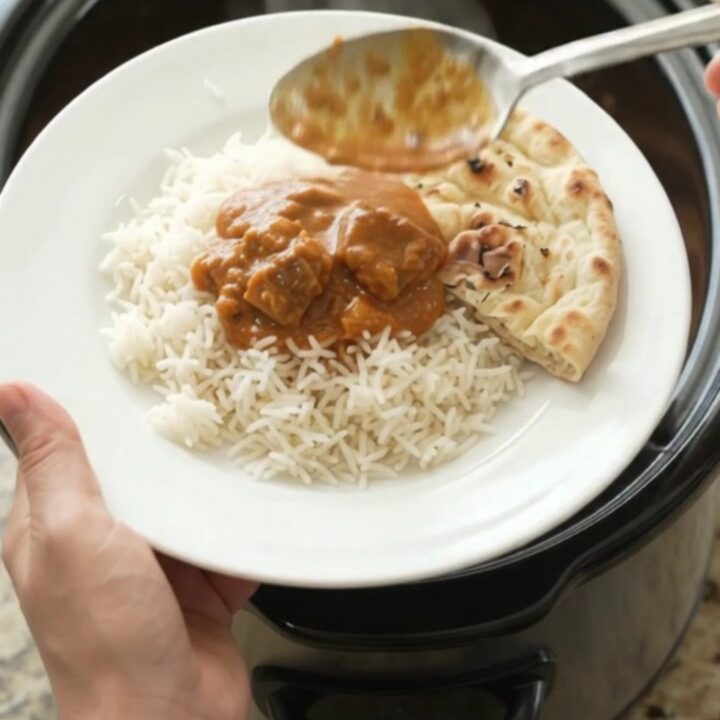 Slow-cooker makhani lamb with orange-red sauce in a black crockpot