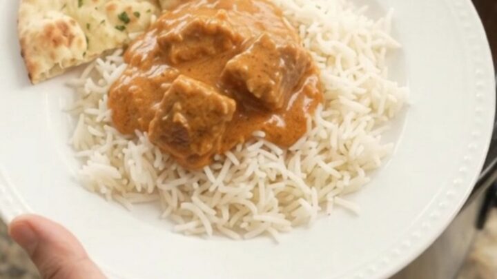Slow cooker filled with creamy makhani lamb curry, garnished with a swirl of cream