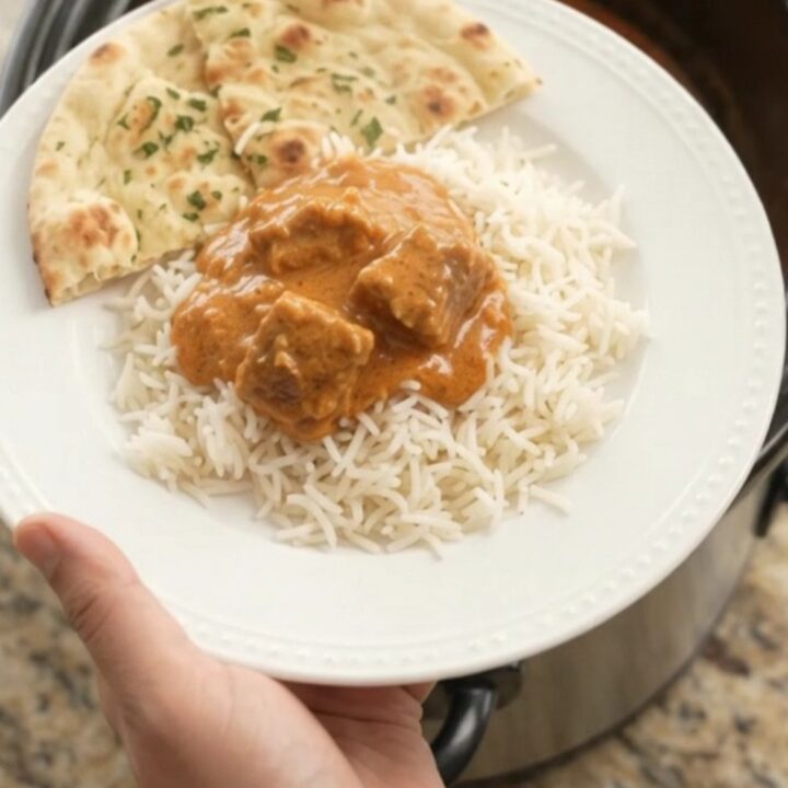 Slow cooker filled with creamy makhani lamb curry, garnished with a swirl of cream
