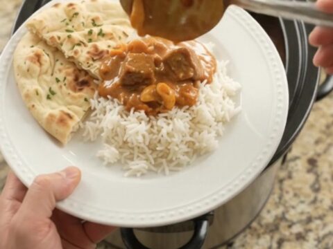 Slow cooker filled with tender lamb cubes in a rich red curry sauce with peppers and bamboo shoots