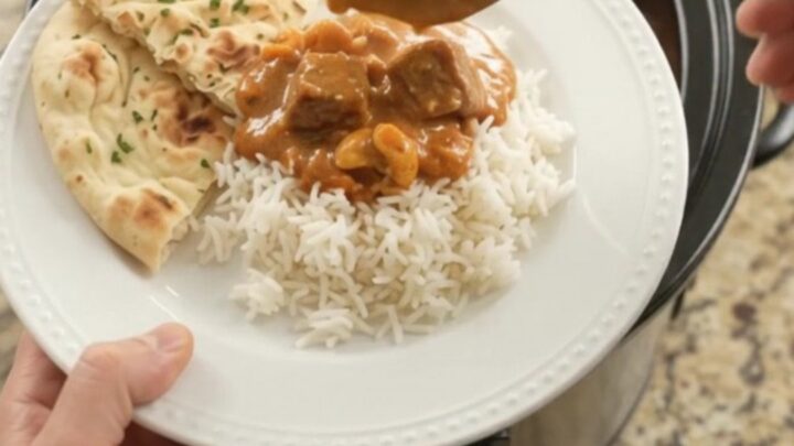 Slow cooker filled with tender lamb cubes in a rich red curry sauce with peppers and bamboo shoots