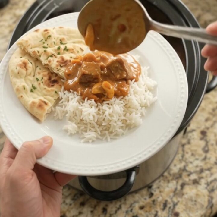 Slow cooker filled with tender lamb cubes in a rich red curry sauce with peppers and bamboo shoots