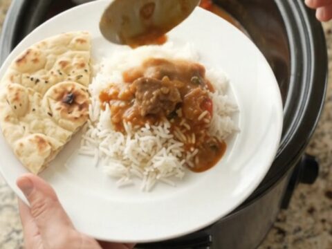 Slow cooker filled with bubbling red curry lamb, peppers, and bamboo shoots