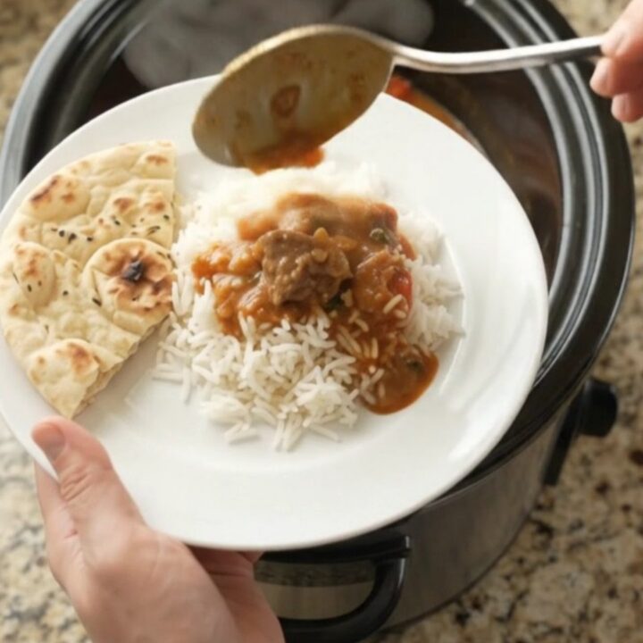 Slow cooker filled with bubbling red curry lamb, peppers, and bamboo shoots