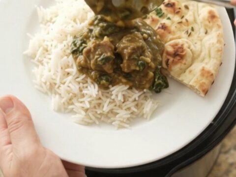 Bubbling Crockpot of garlic butter spinach saag lamb cubes with creamy green sauce