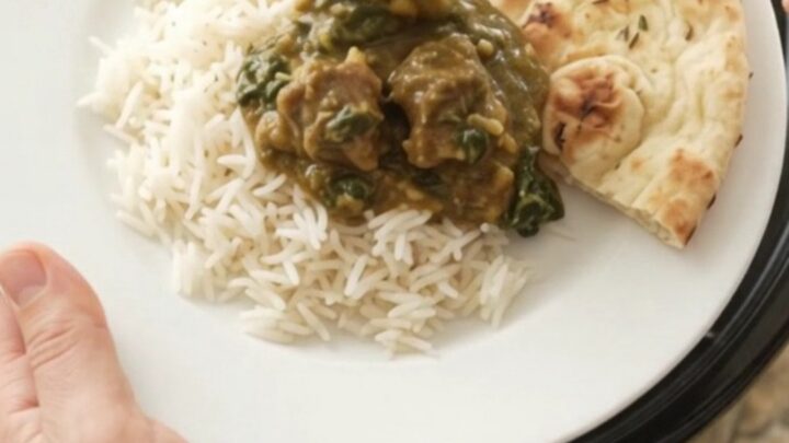 Bubbling Crockpot of garlic butter spinach saag lamb cubes with creamy green sauce