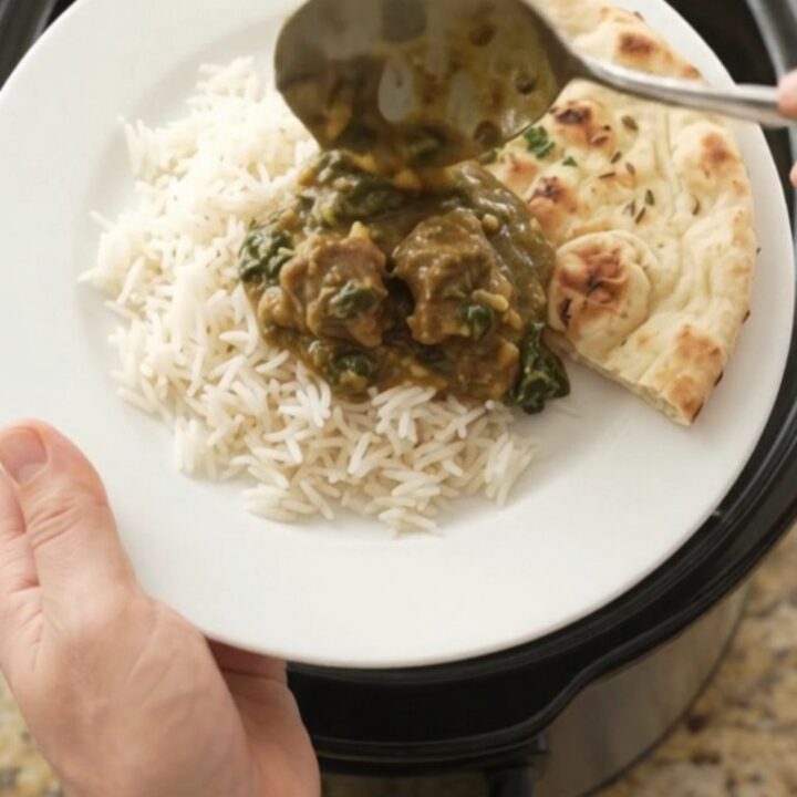 Bubbling Crockpot of garlic butter spinach saag lamb cubes with creamy green sauce